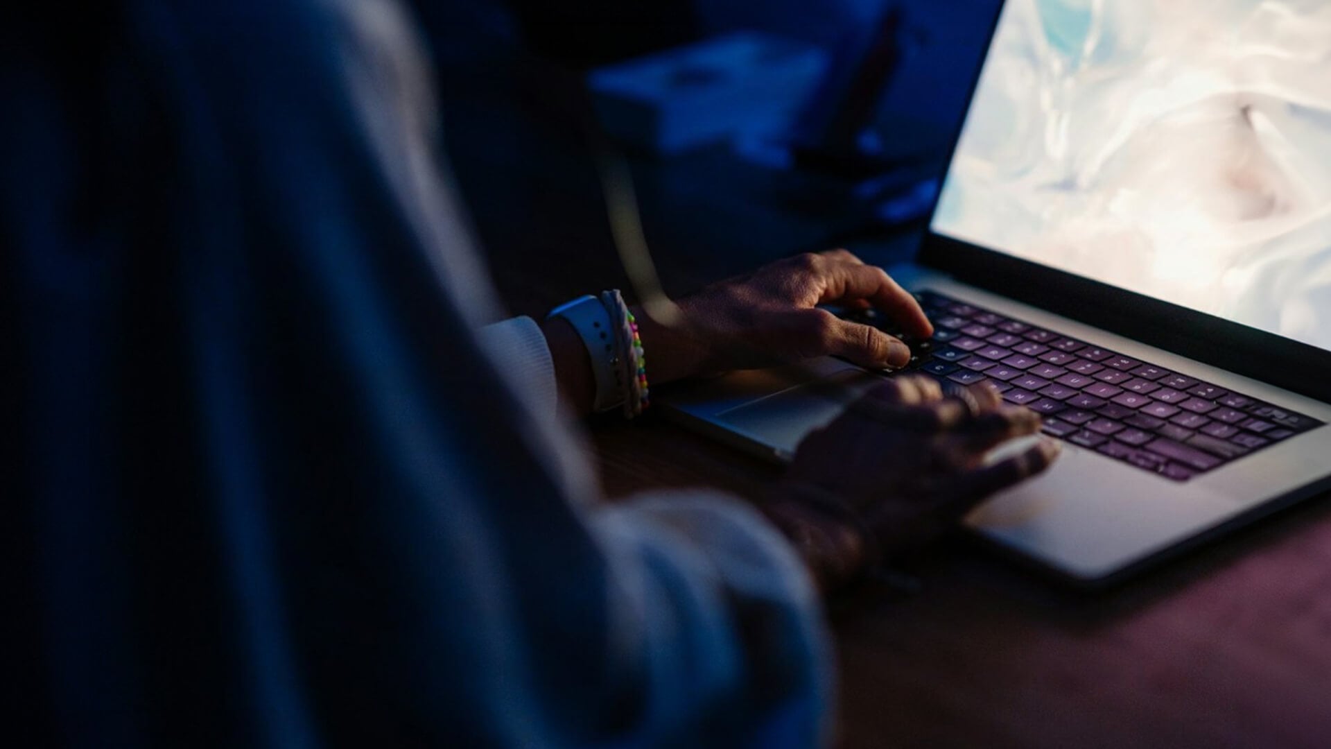 Close-up of hands typing on a laptop keyboard during a late-night AI coding or local model session.