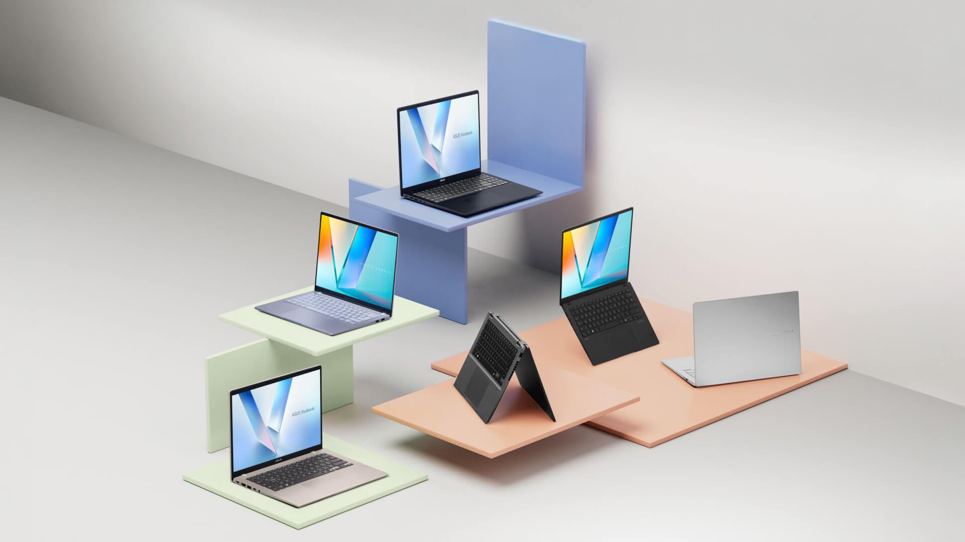 Group of slim ASUS VivoBook laptops on colorful stands.