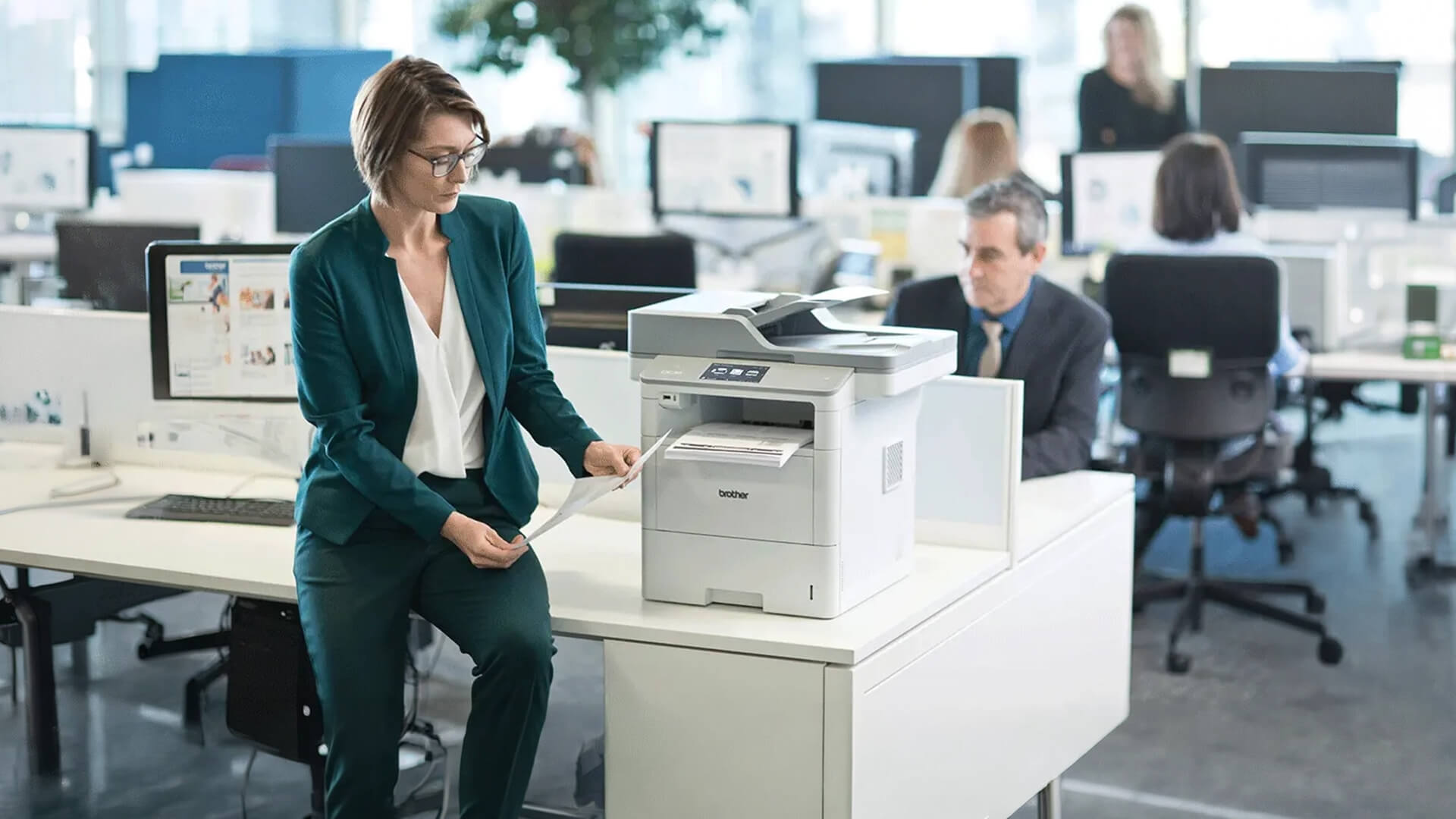 Woman using an automatic duplex Brother printer in a busy office.