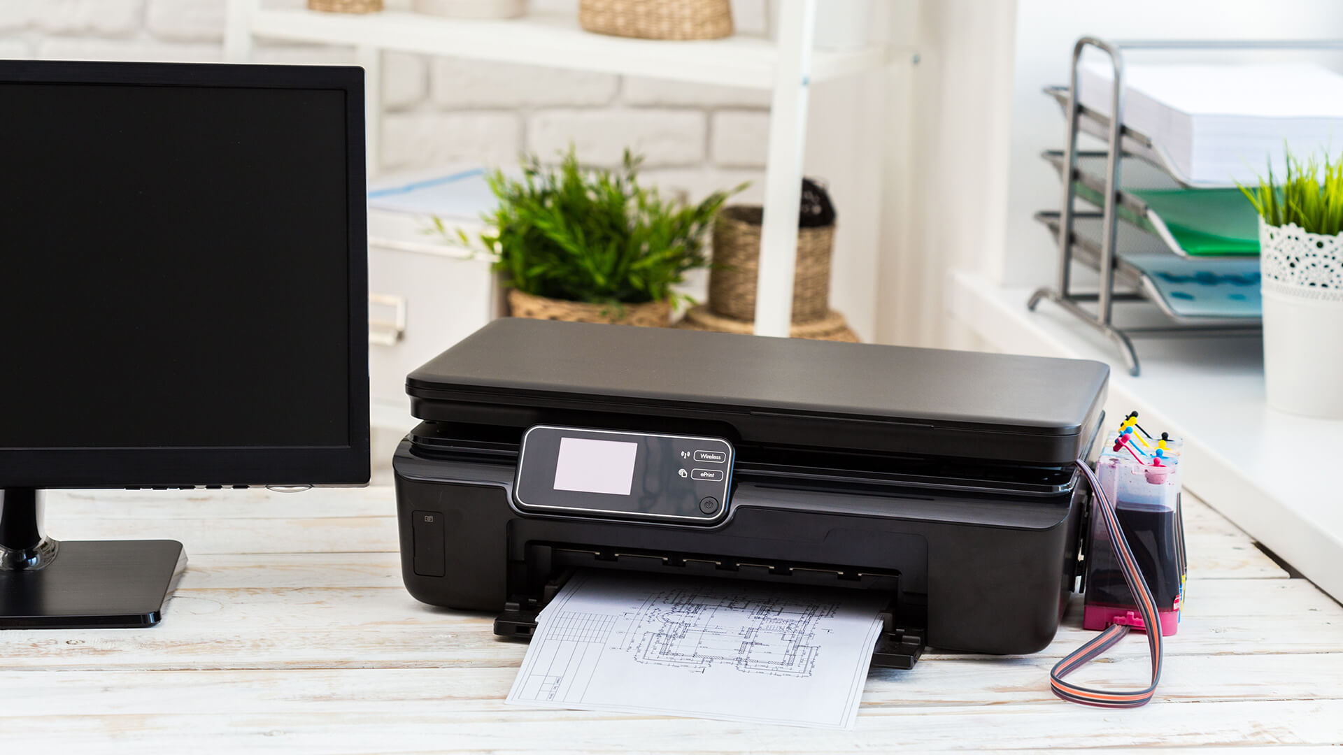 Black ink tank printer on a desk printing business plans.