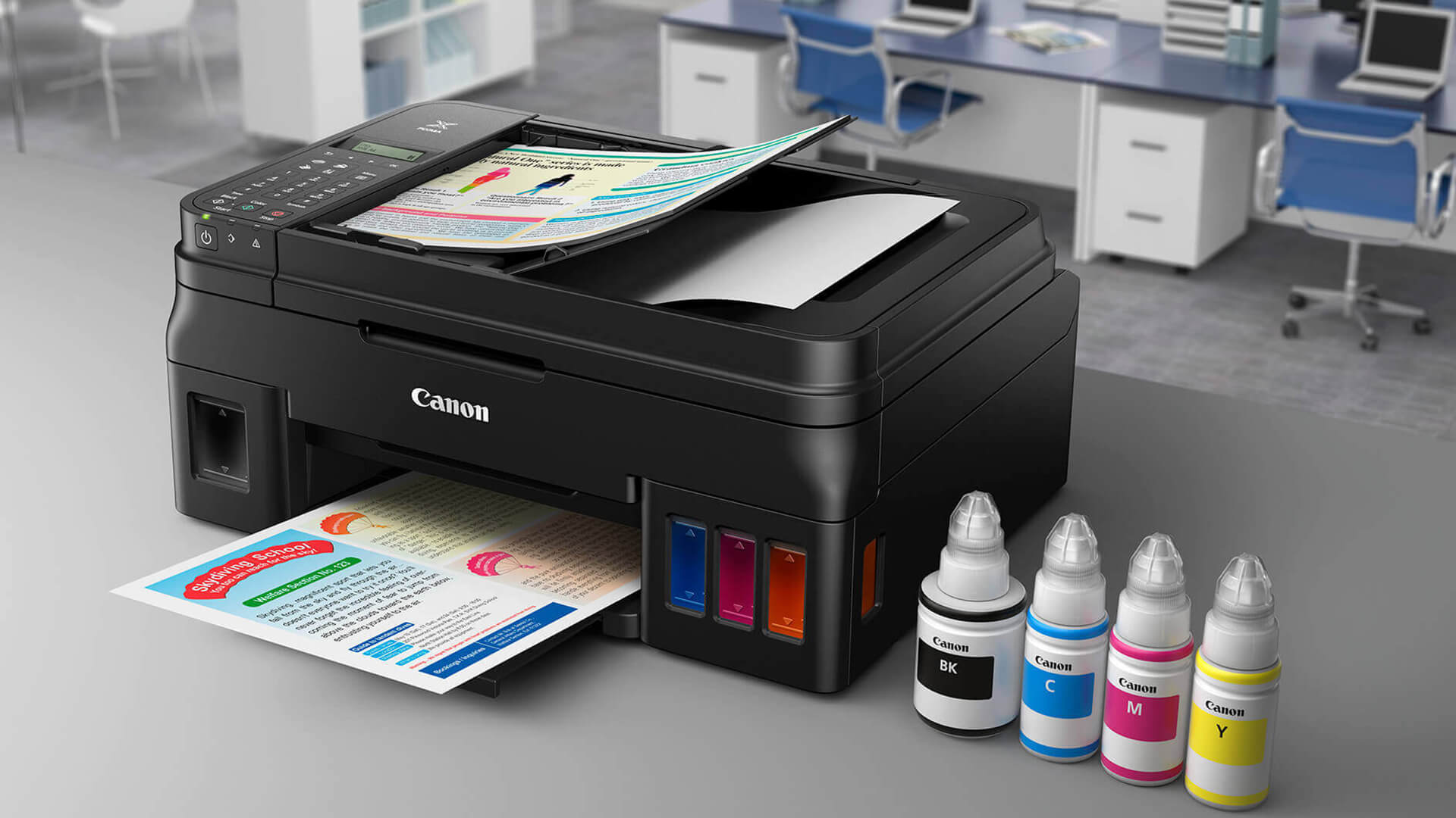 Canon PIXMA printer with four ink bottles sitting on a desk.