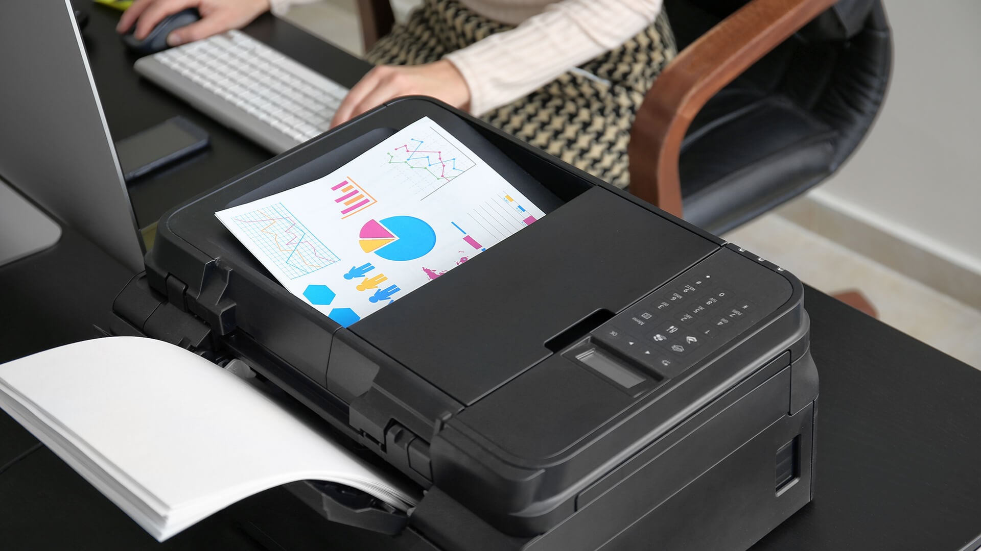 Woman taking a double-sided document from a compact office printer.