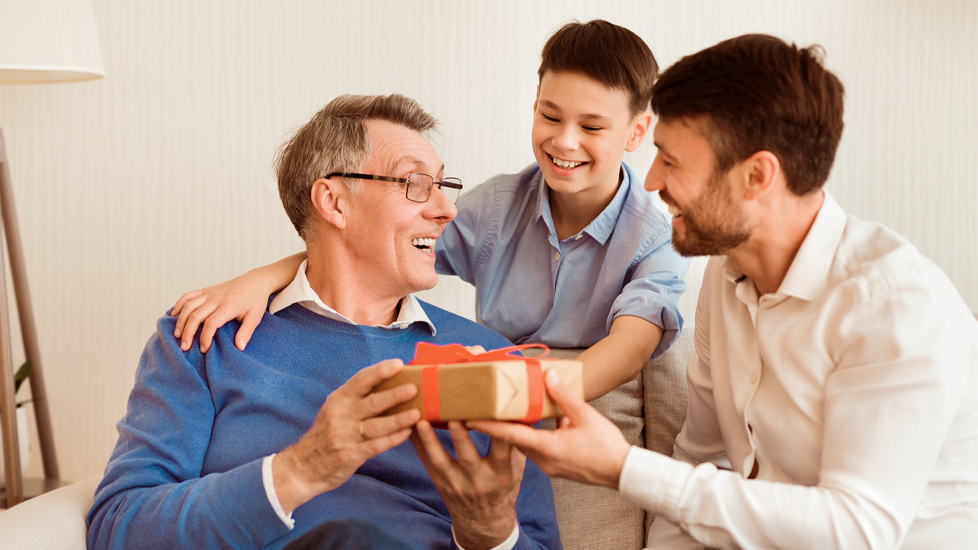 on and grandson giving a wrapped Father's Day gift to grandad.