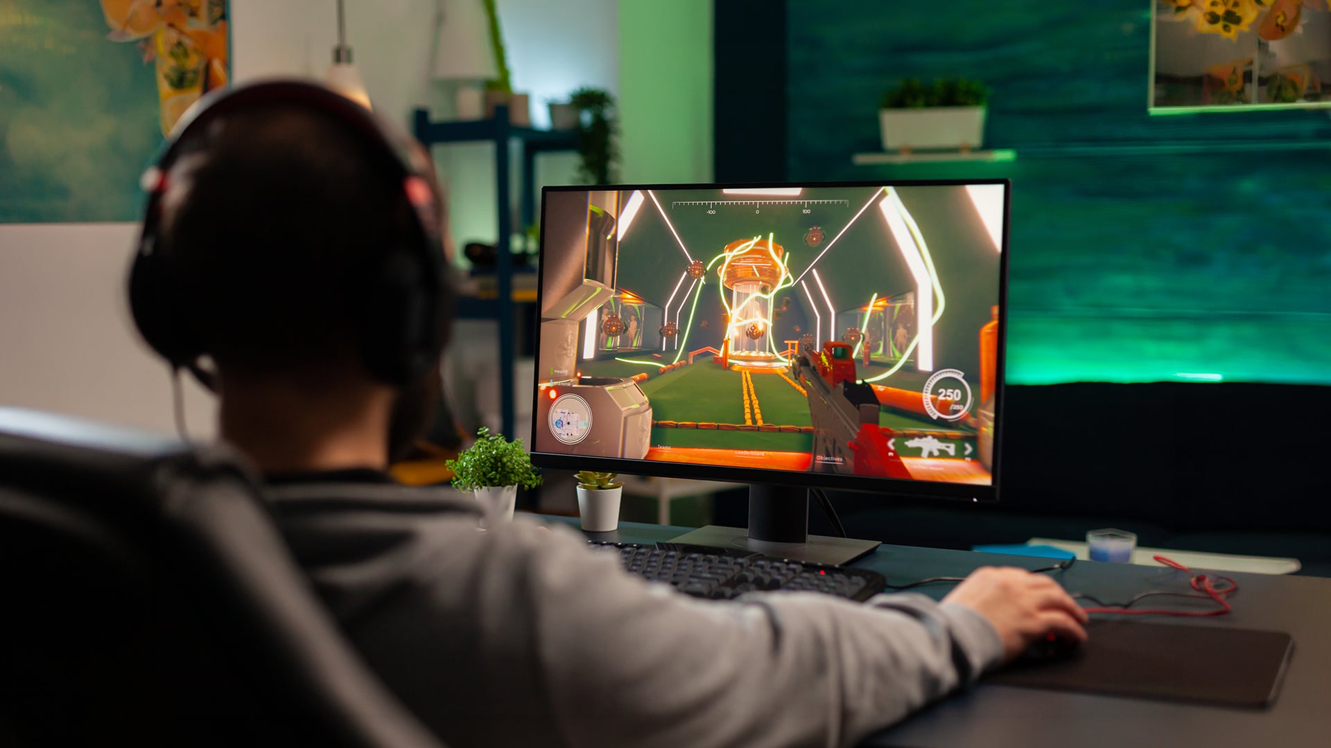 Over-the-shoulder view of a gamer playing a first-person shooter game with a mouse and keyboard.