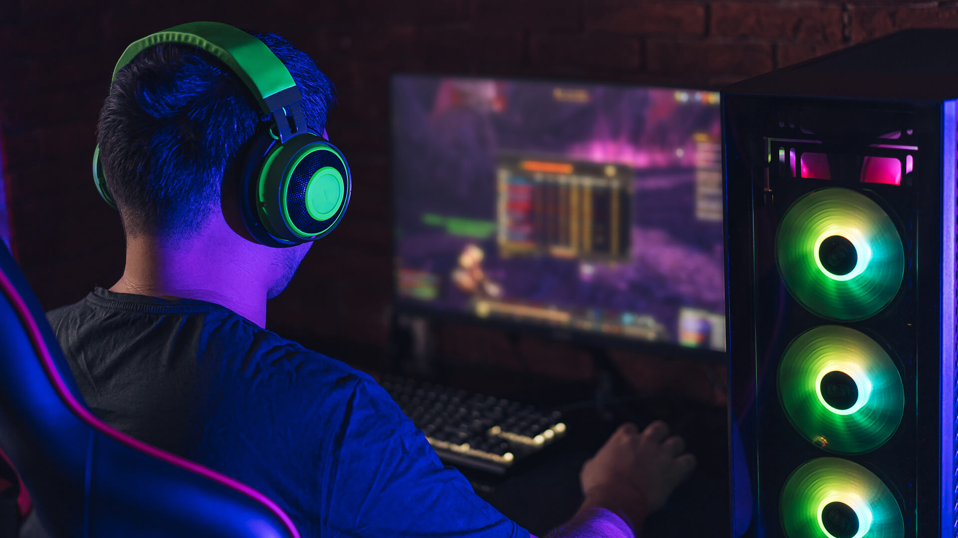 Gamer wearing a green headset looking at a desktop PC monitor.