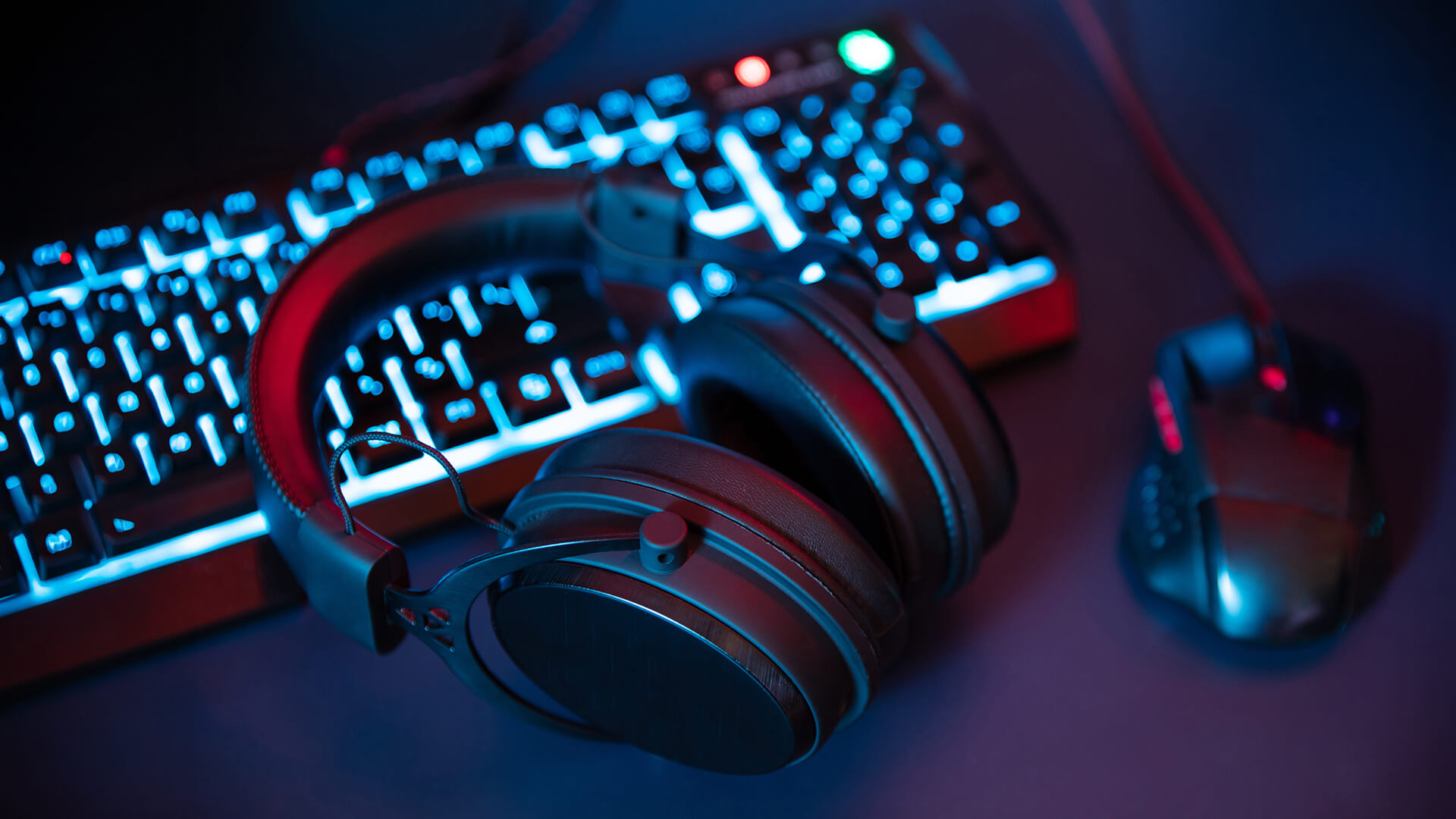 Gaming headset on a desk with an RGB keyboard and mouse.