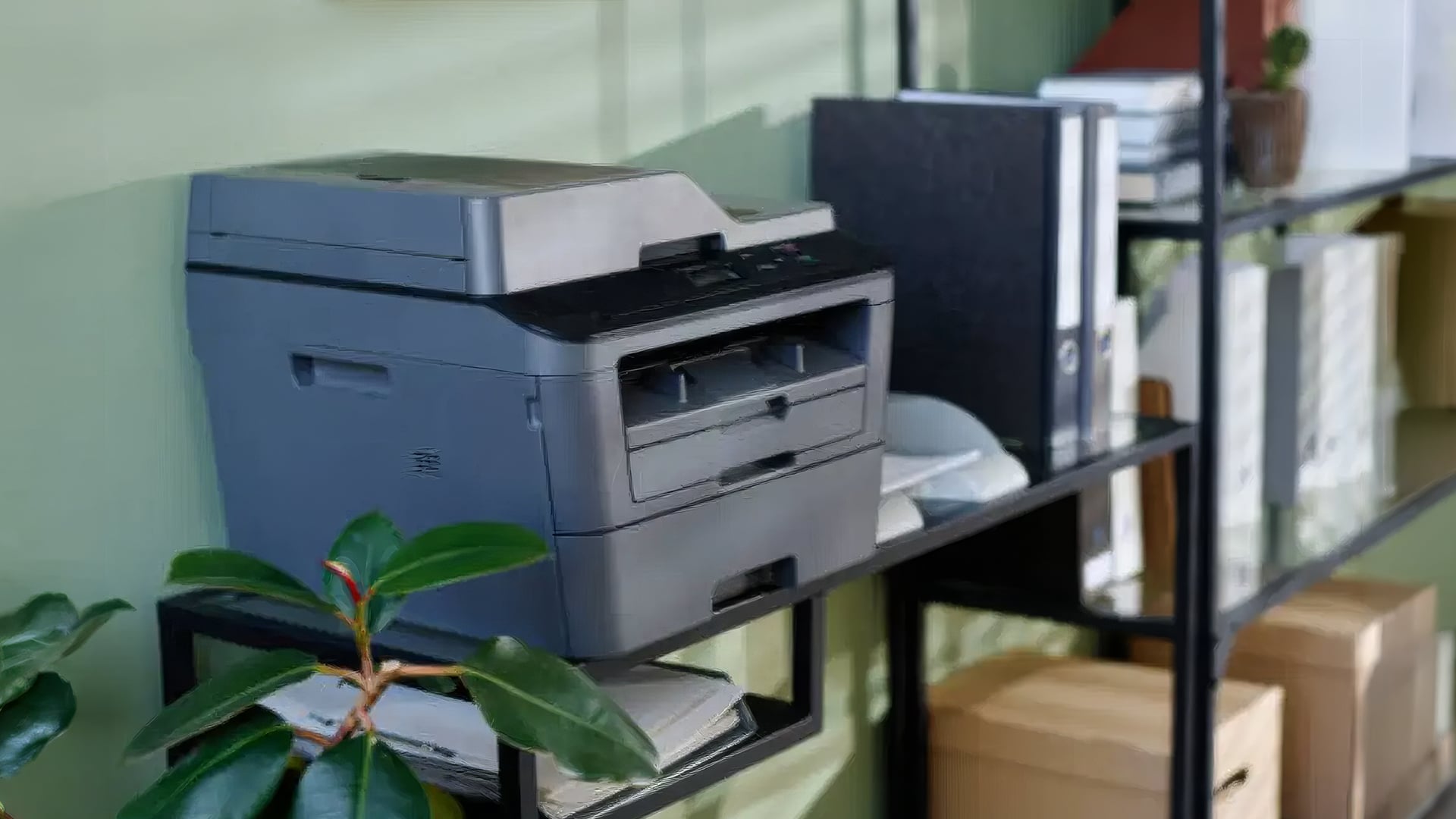 Grey multifunction laser printer on an office shelf.