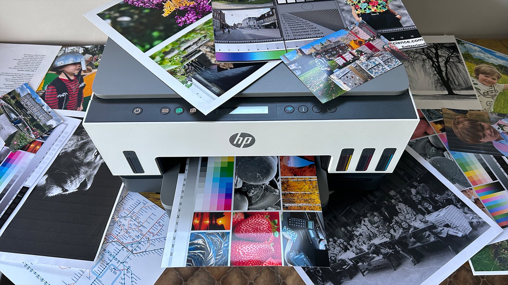 HP Smart Tank printer surrounded by various printed color photos.