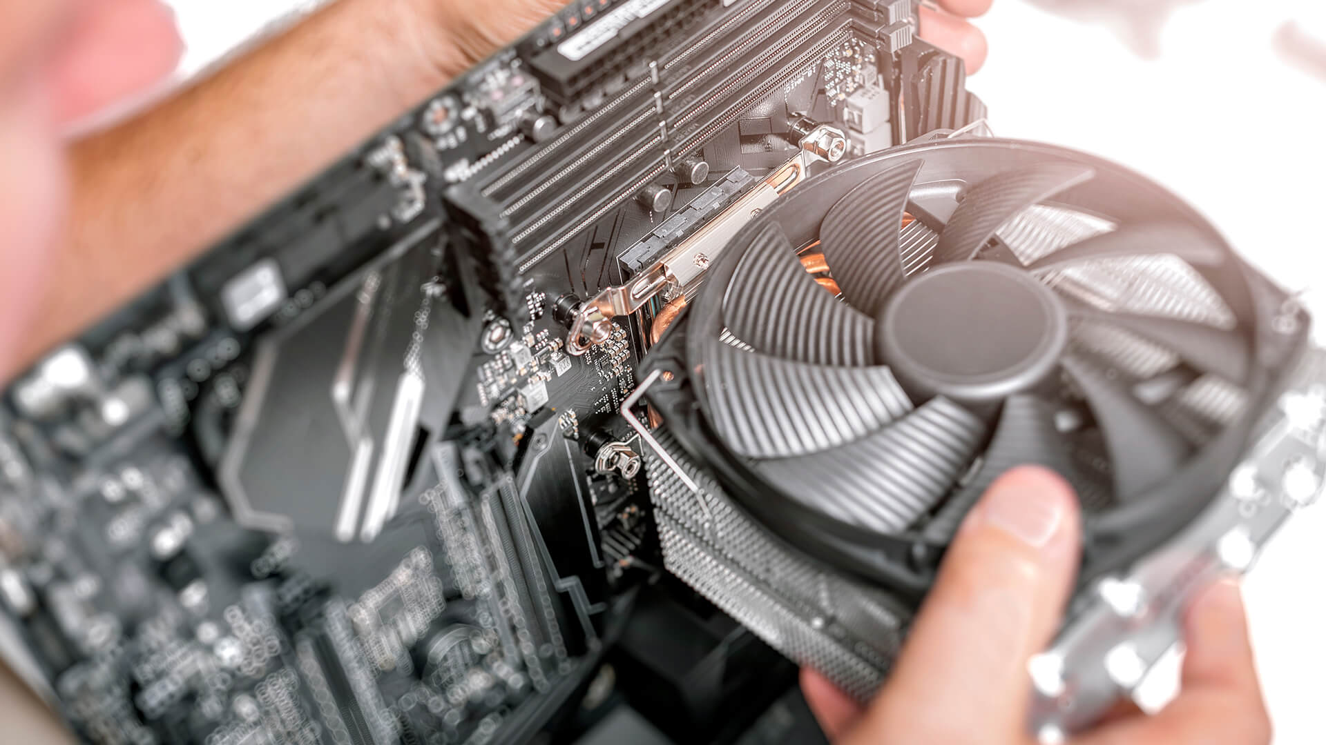 Hands installing a CPU air cooler onto a motherboard.