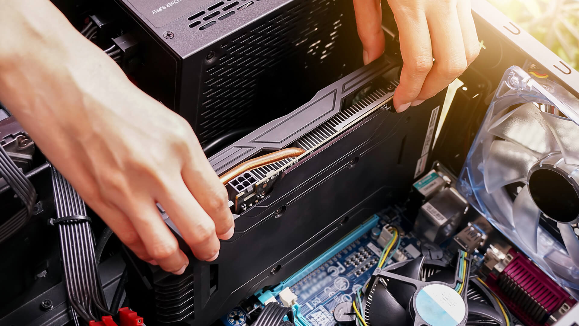 Close-up of hands carefully fitting a graphics card into a motherboard PCIe slot.