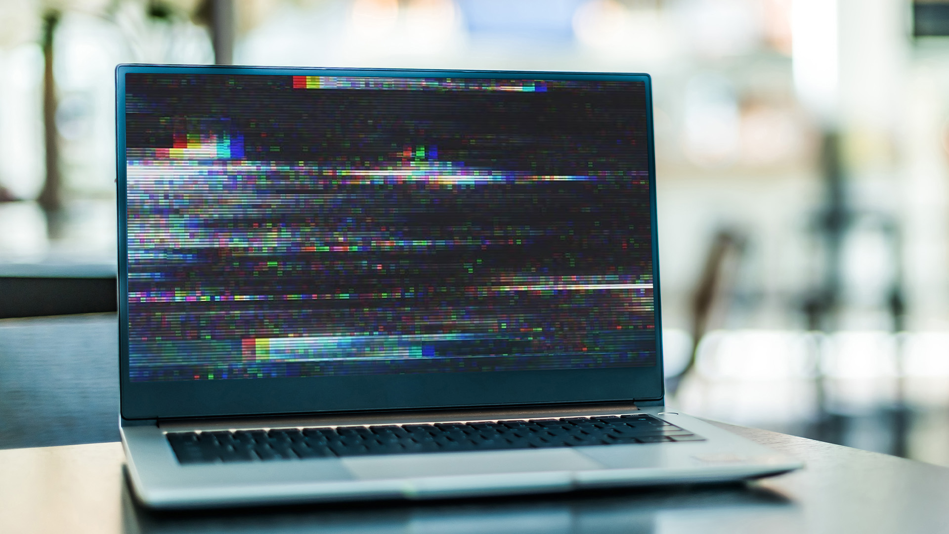 Laptop display showing severe horizontal glitch lines and colorful static noise.