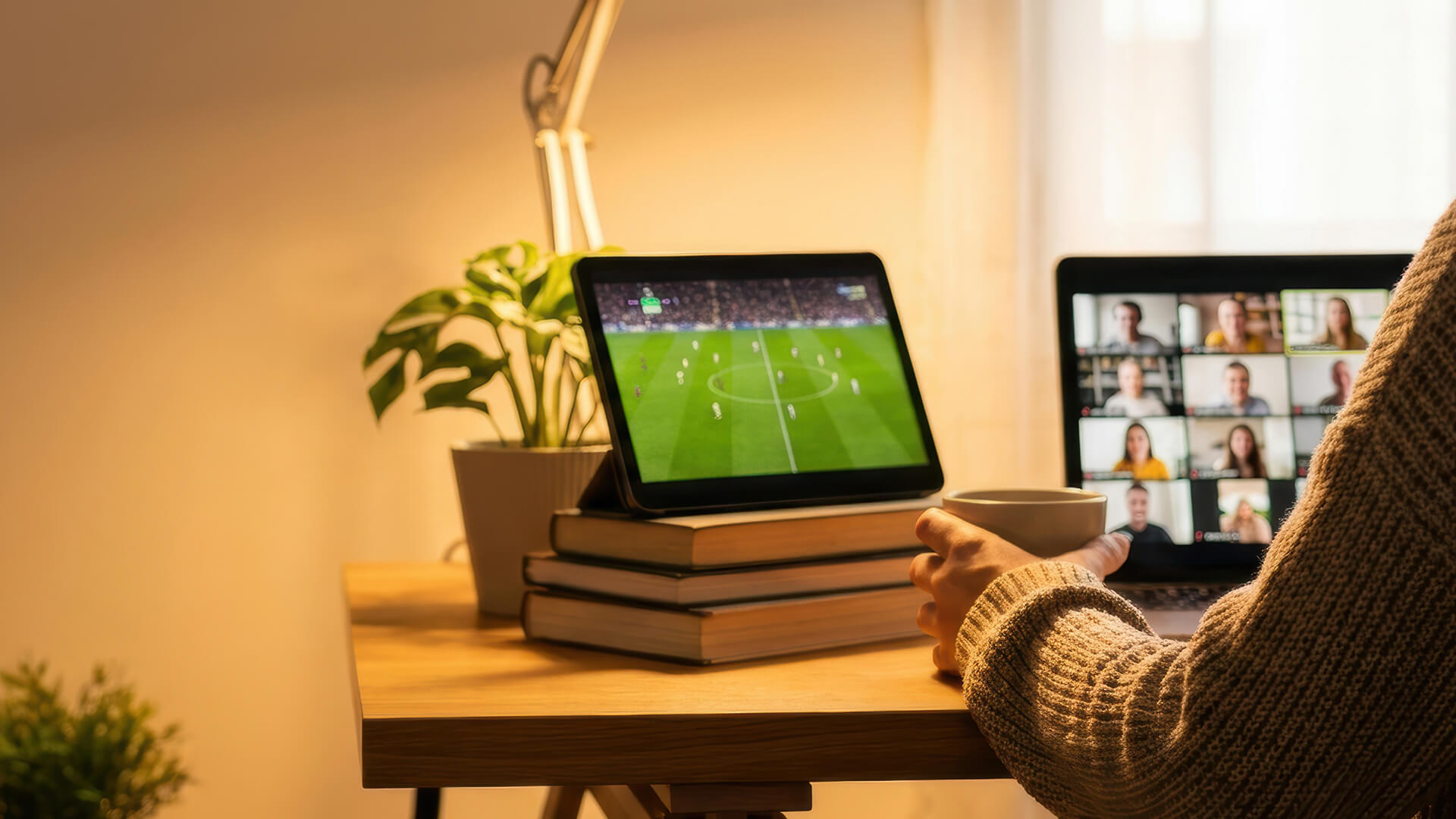 Fan with headphones cheering at a football stream on a laptop.