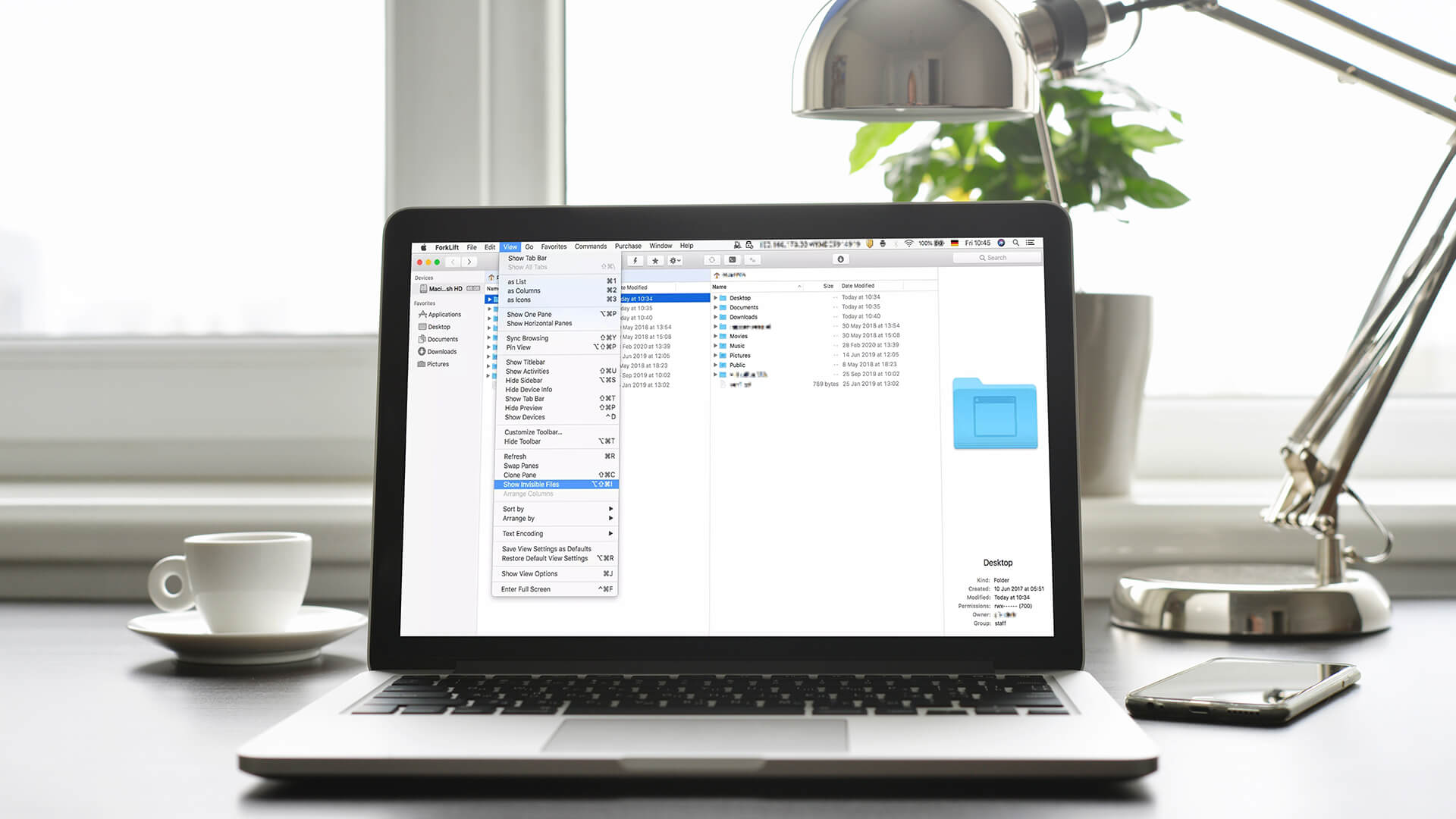 MacBook on a desk showing Finder view settings and hidden files.