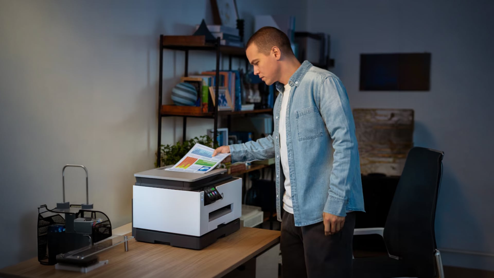 Man standing by an HP printer holding a color chart document.
