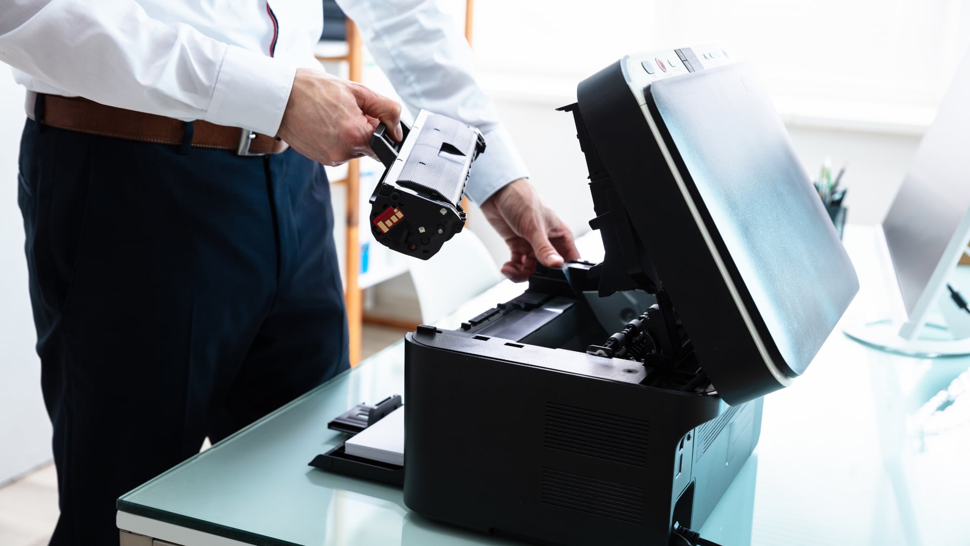 Man replacing a black toner cartridge in an office printer.