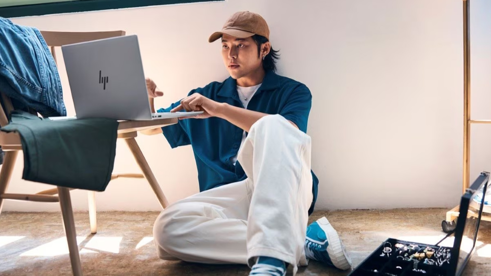 Woman looking intently at a silver HP laptop on a cafe table.