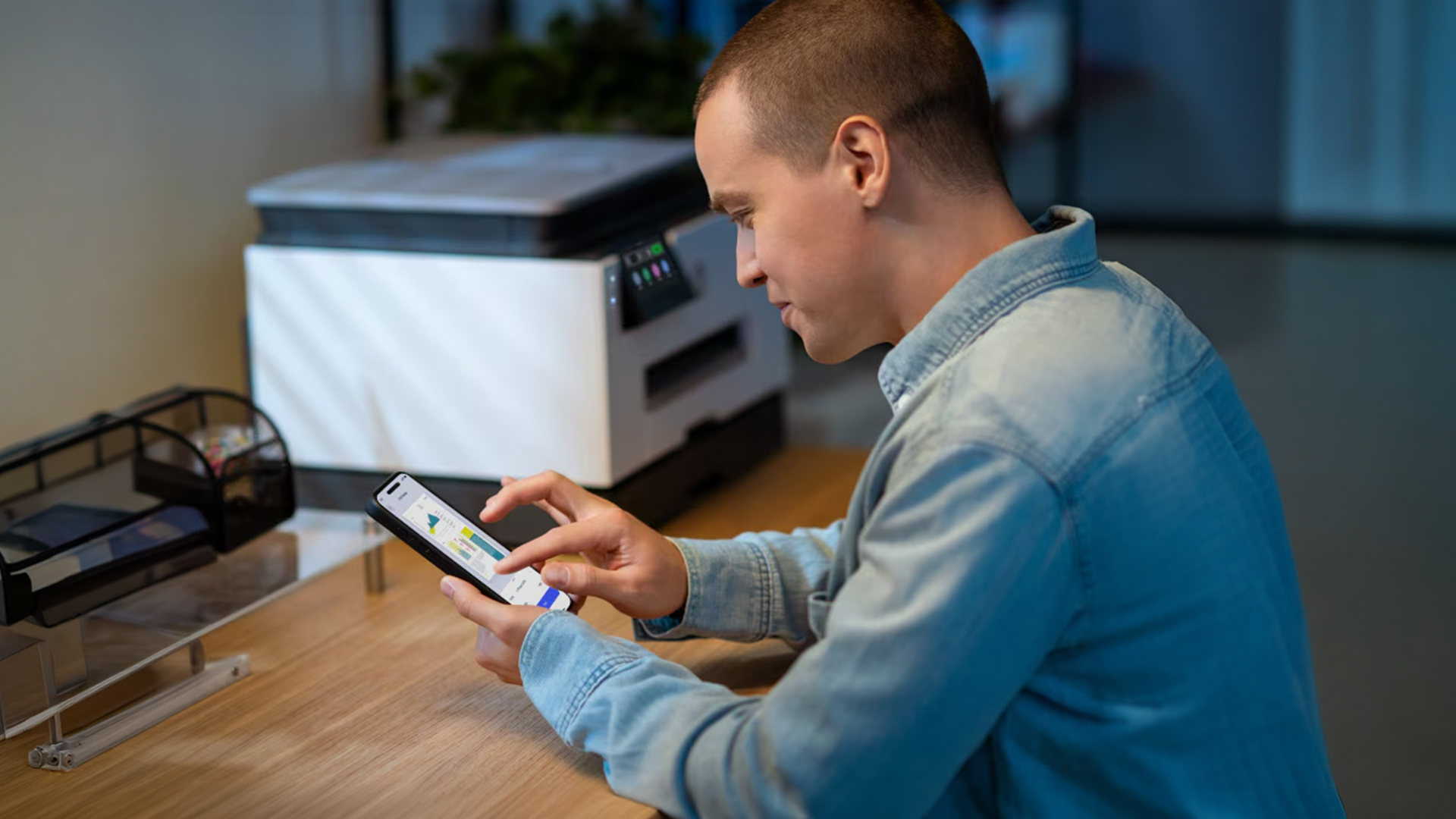 Man using a smartphone app next to an HP office printer.