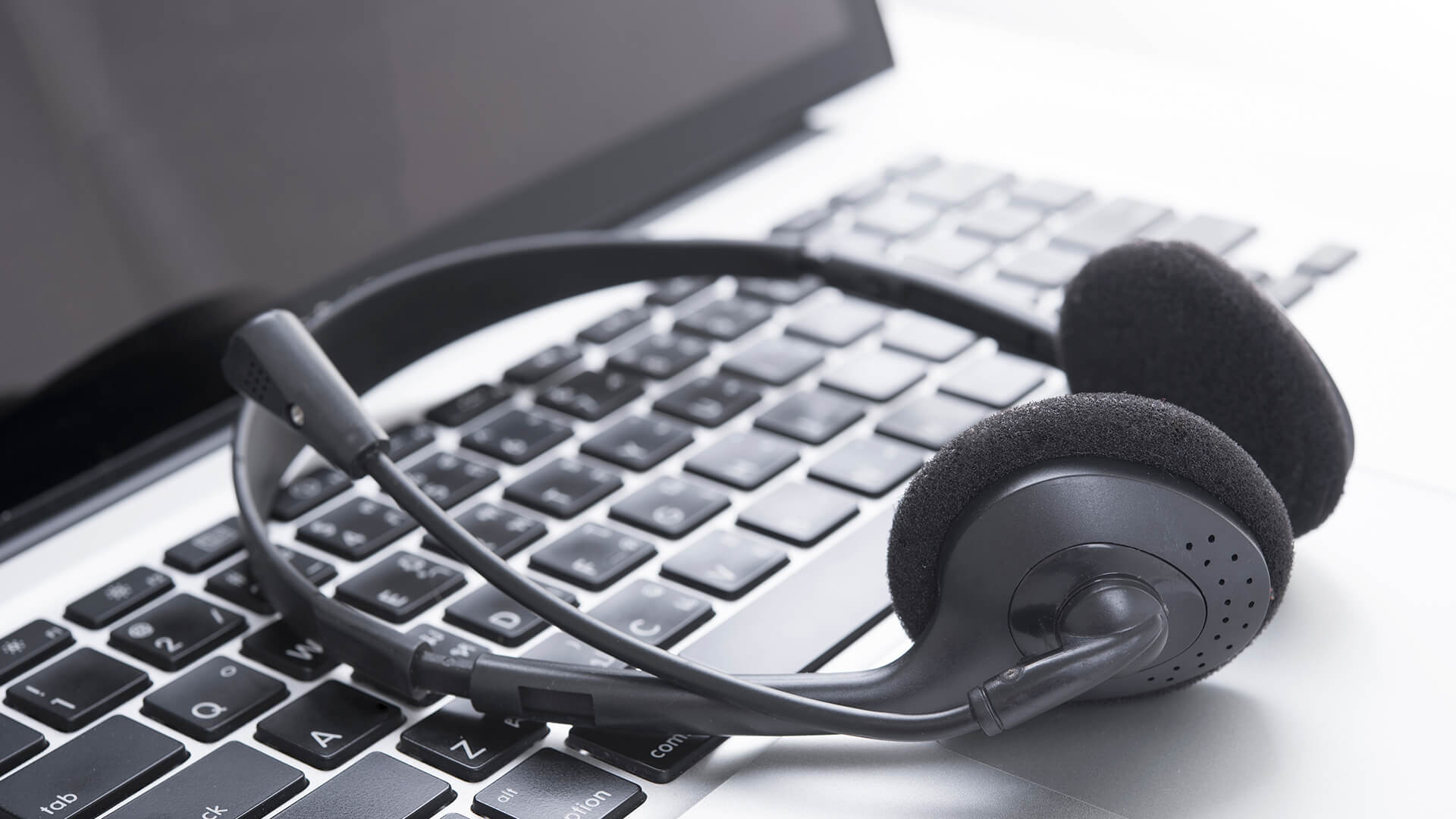 Office headset with a microphone resting on a laptop.