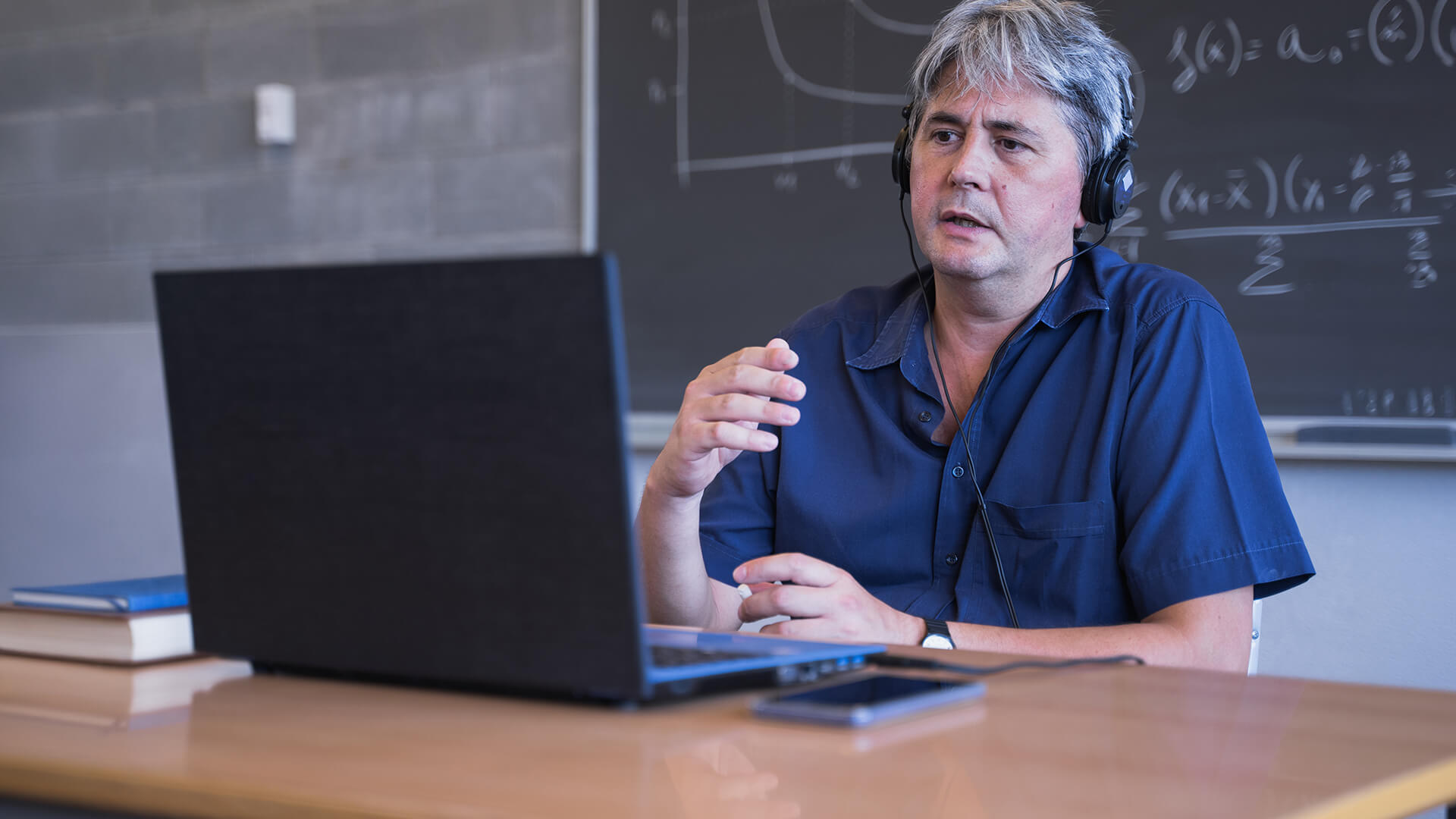 Teacher using a laptop and headset for online classes.