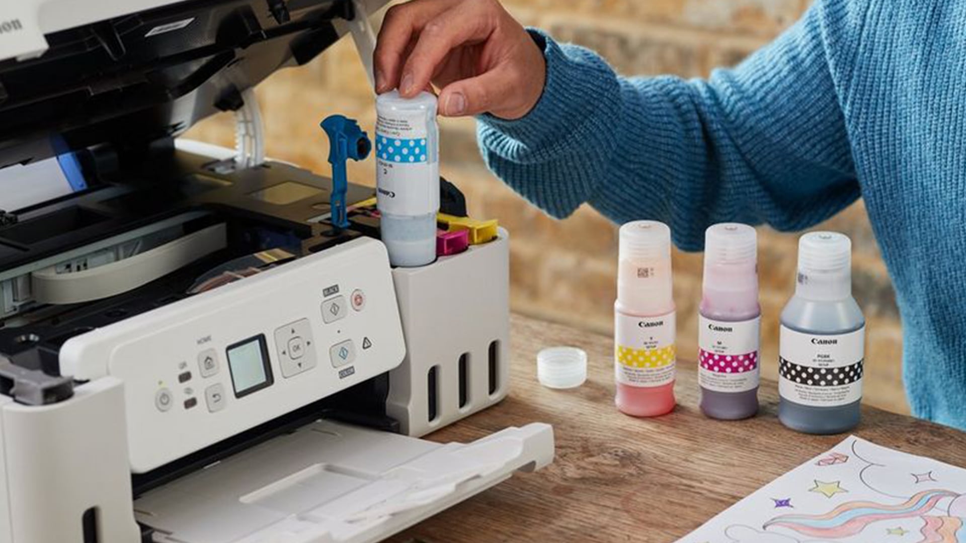 Person refilling a white Canon printer with ink.
