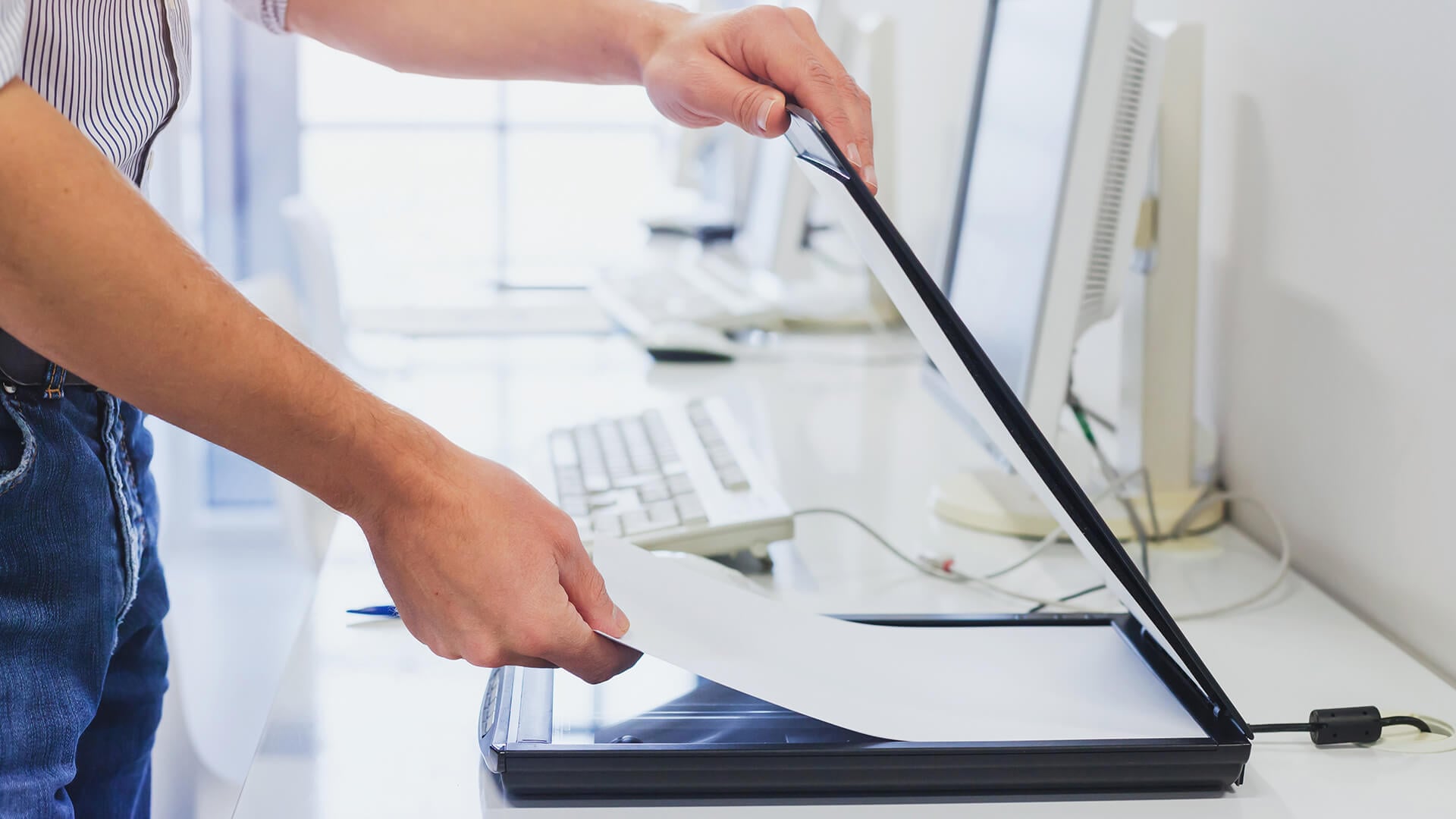 A person placing a document onto a dedicated flatbed scanner.