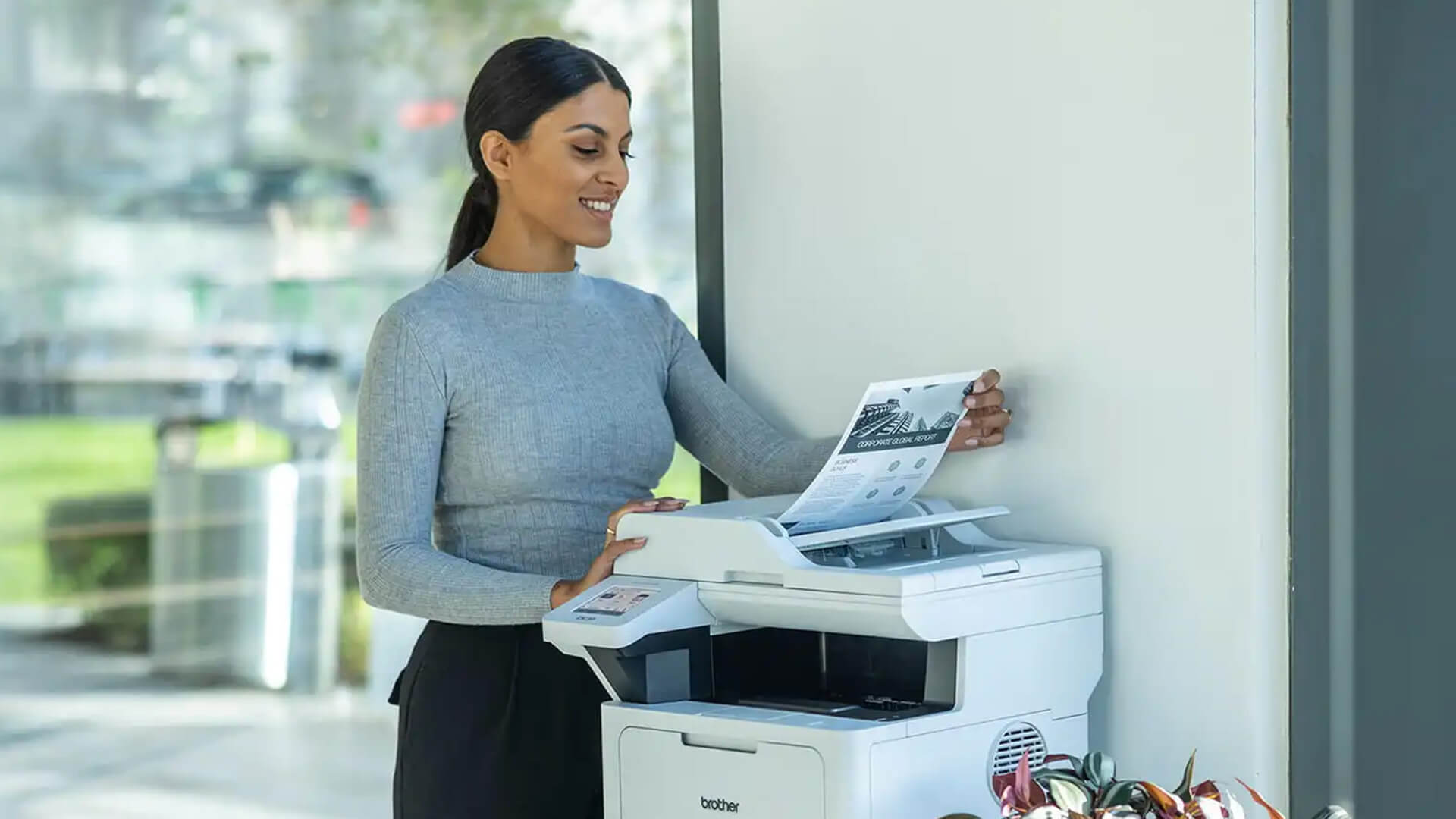Professional woman using a Brother MFC printer in an office.