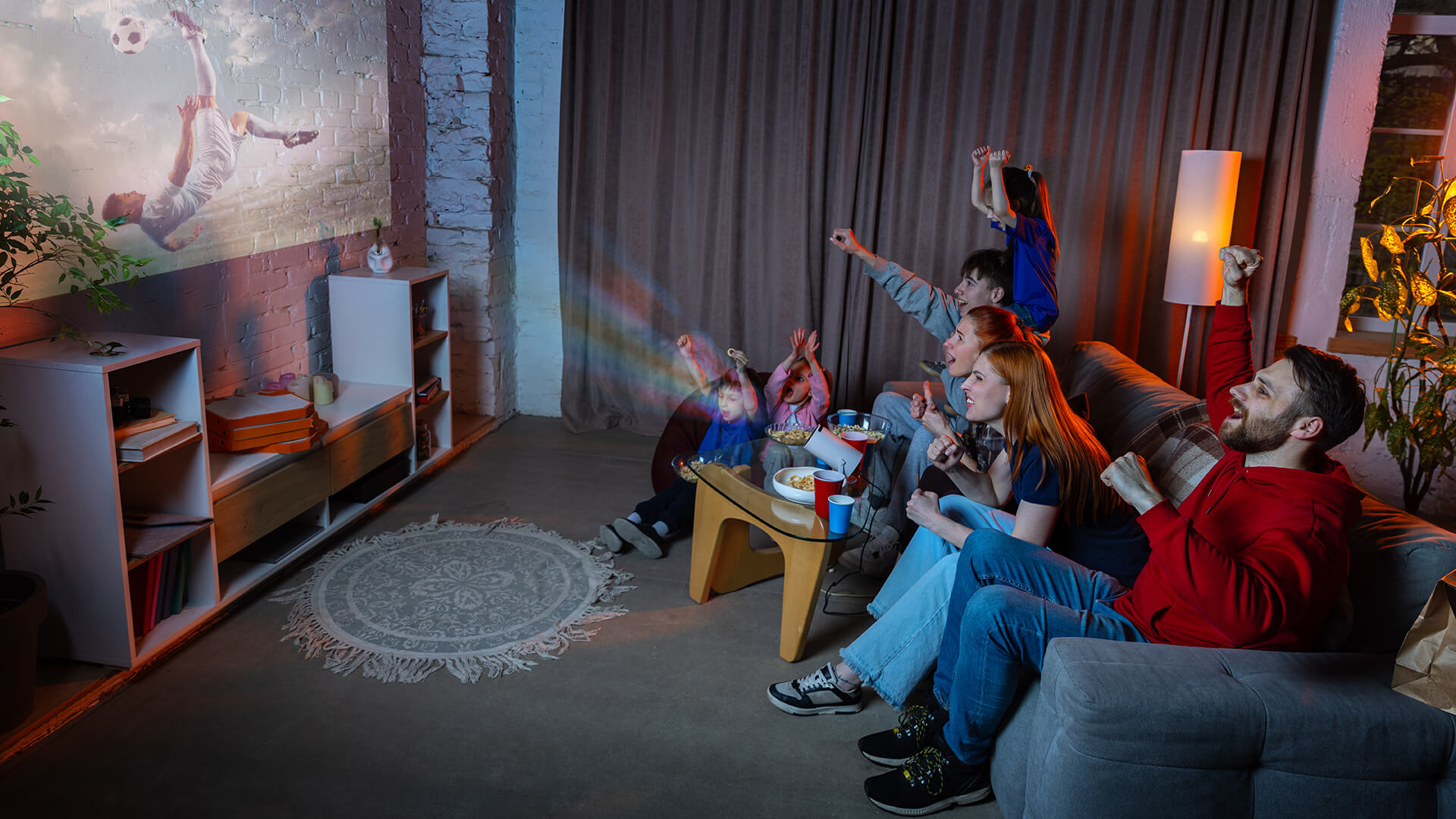 rowd watching a football match on a massive projector screen.