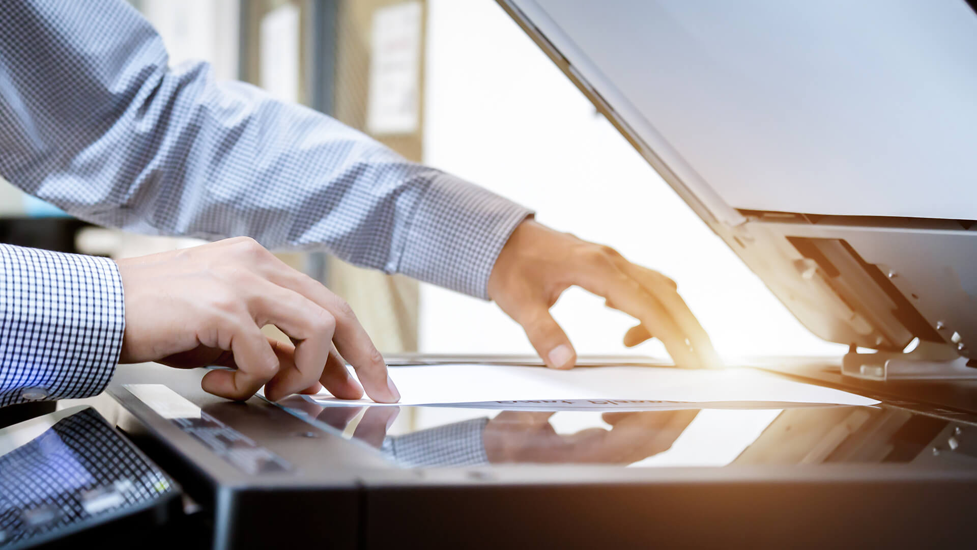 Hands placing a paper on a printer flatbed scanner.