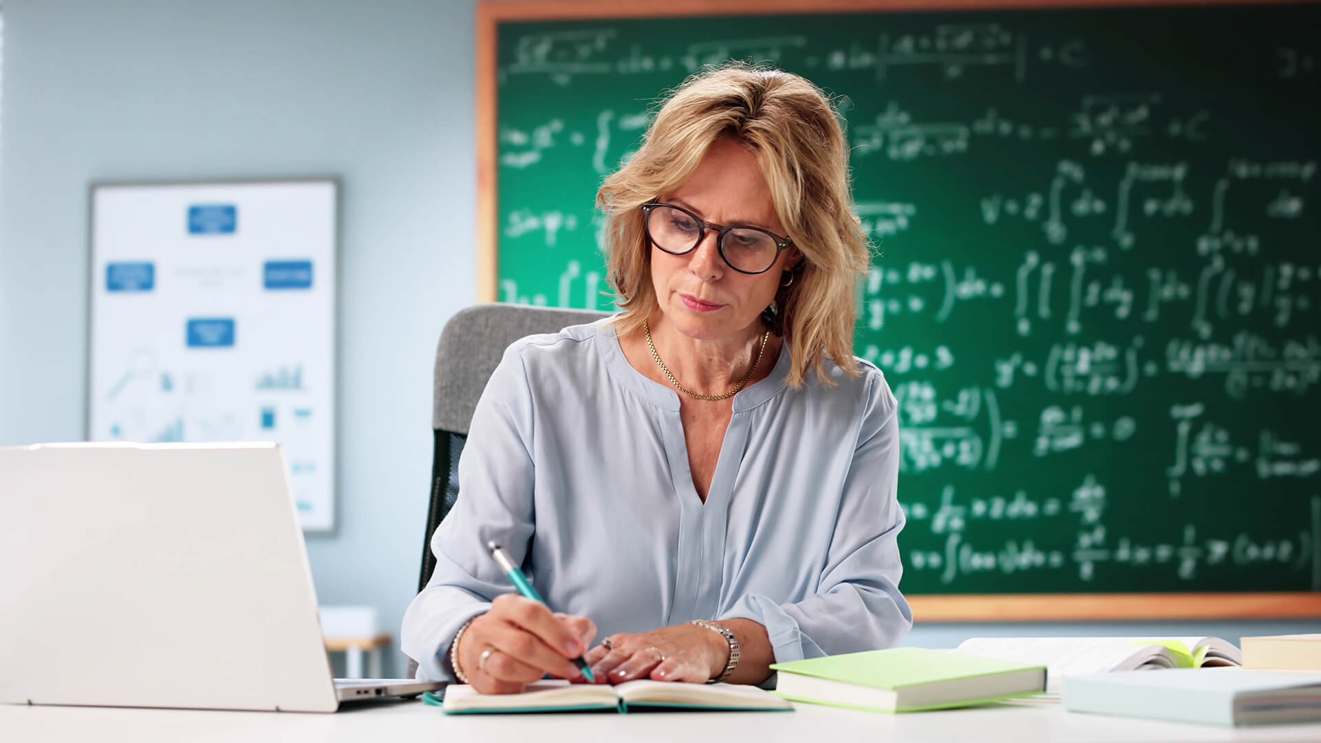 Teacher planning lessons with a laptop at her desk.