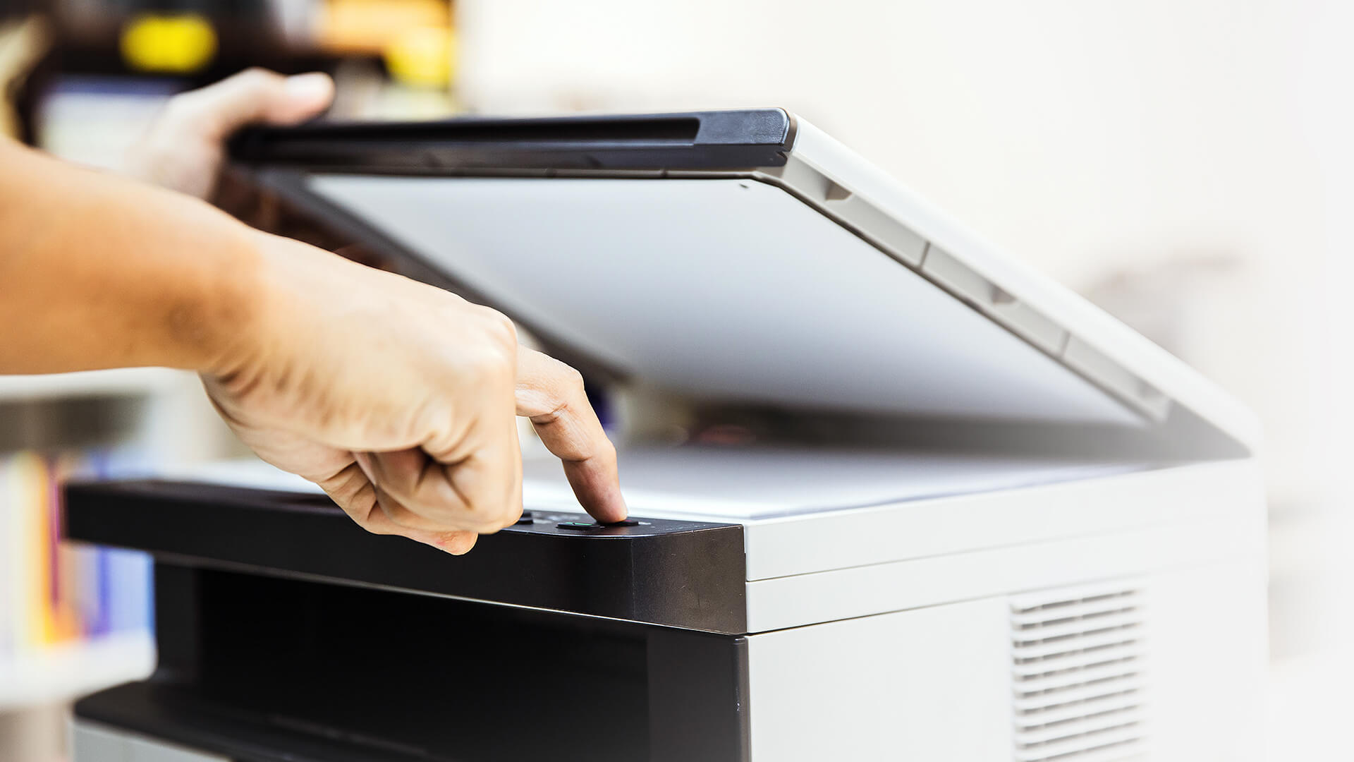 Person pressing the start button on a multifunction printer.
