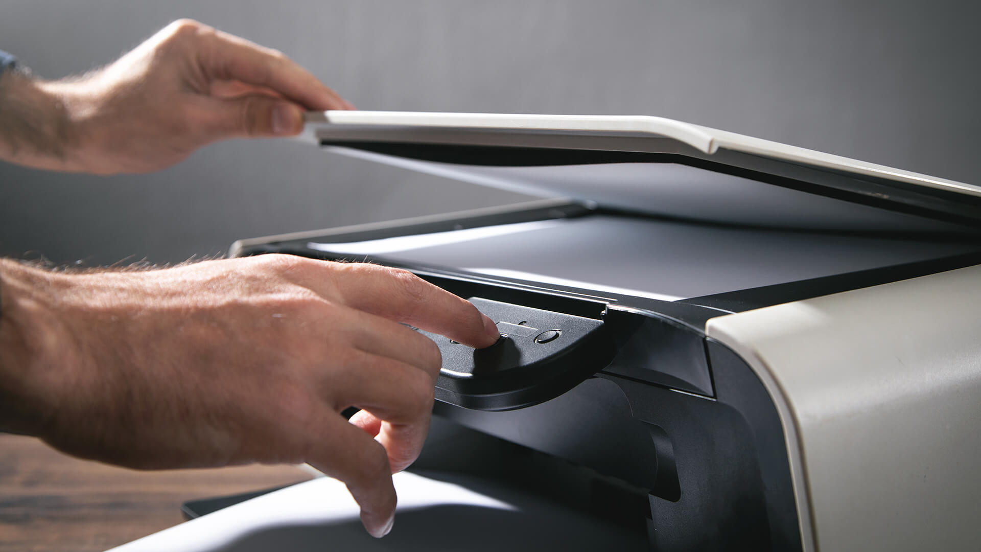 Close-up of a person pressing the scan button on an all-in-one printer.