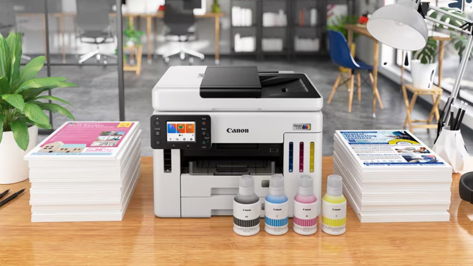 White Canon MegaTank printer with ink bottles on a desk.