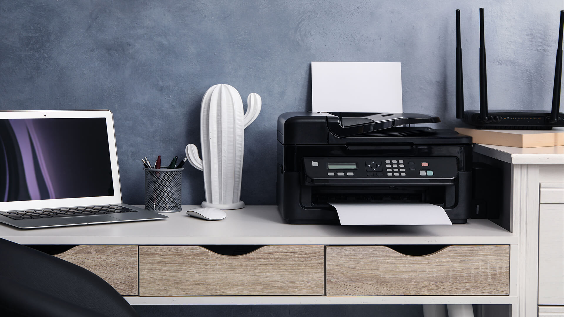 Wireless printer next to a laptop and Wi-Fi router.