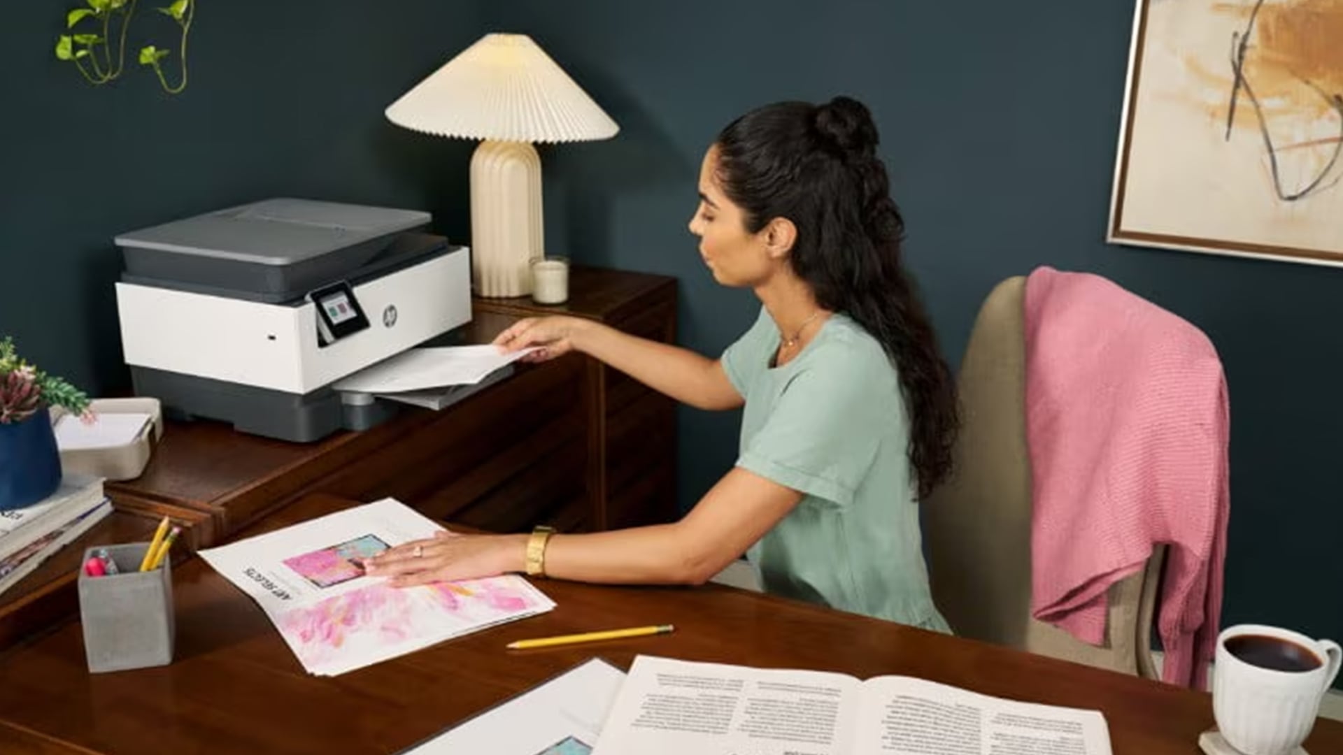 Woman sitting at a desk taking paper out of an HP printer.